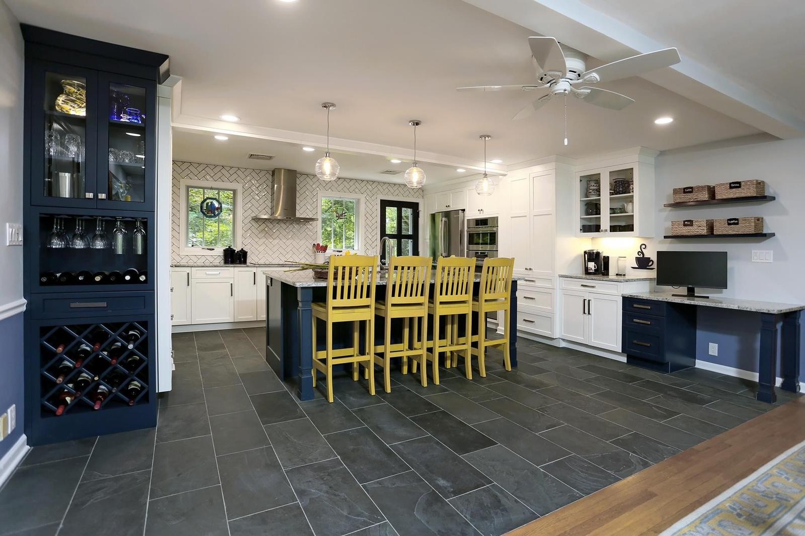 Wide view of remodeled white kitchen with blue island and bar seating